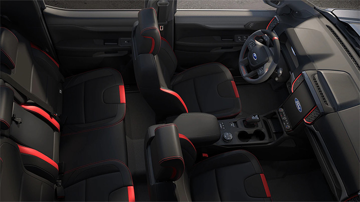 Innenansicht eines Autos mit schwarzen Sitzen und roten Akzenten, zeigt das Cockpit und die Sitze.